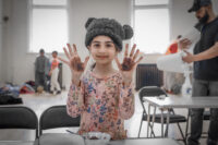 9-year-old Jumaymah who attended Success4All's Spring Holiday Club shows her hands covered in cacao powder from making protein balls.
